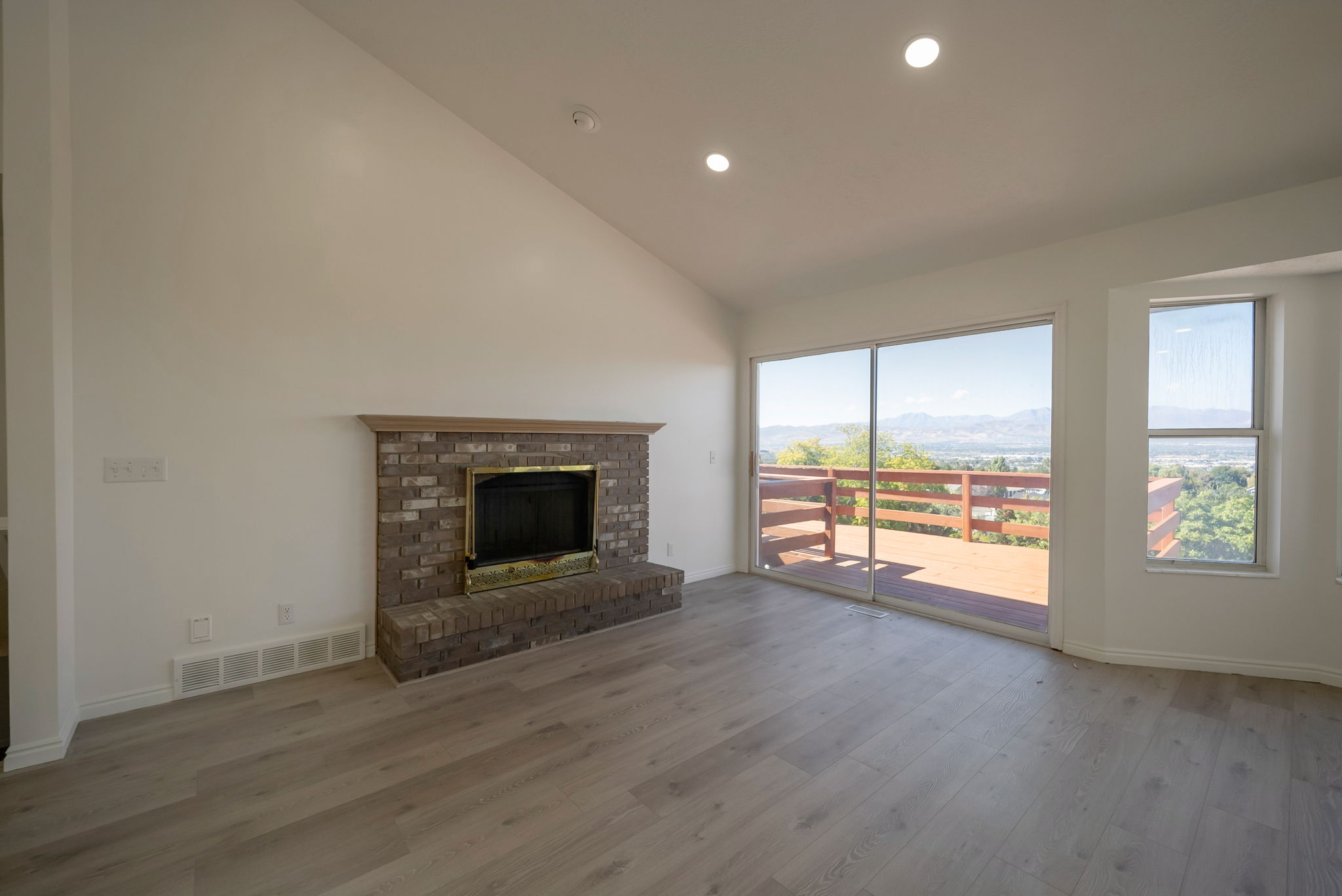 Unfurnished living room featuring a mountain view, a fireplace, light wood-type flooring, lofted ceiling, and recessed lighting