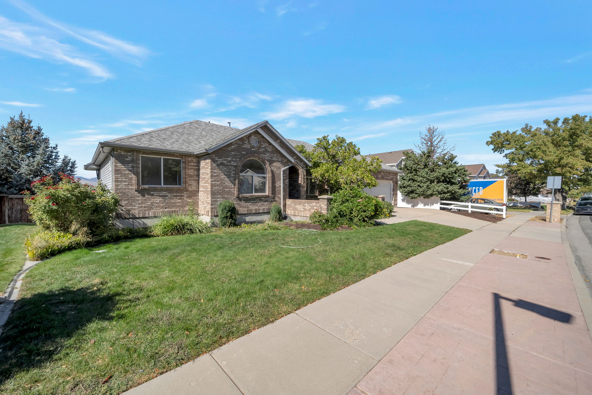 View of front of property with a shingled roof, a front lawn, brick siding, concrete driveway, and an attached garage