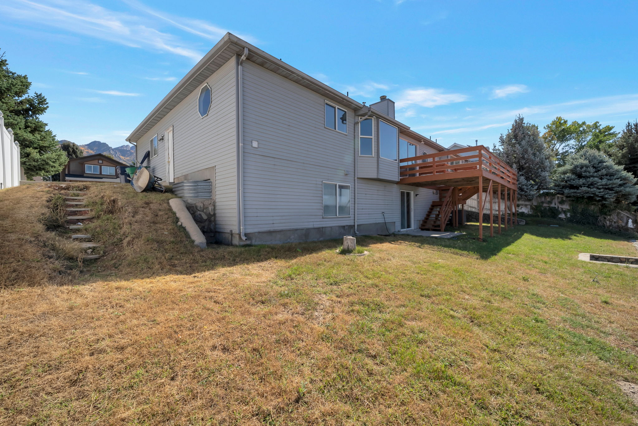 Rear view of house featuring a deck with mountain view, a lawn, and a chimney