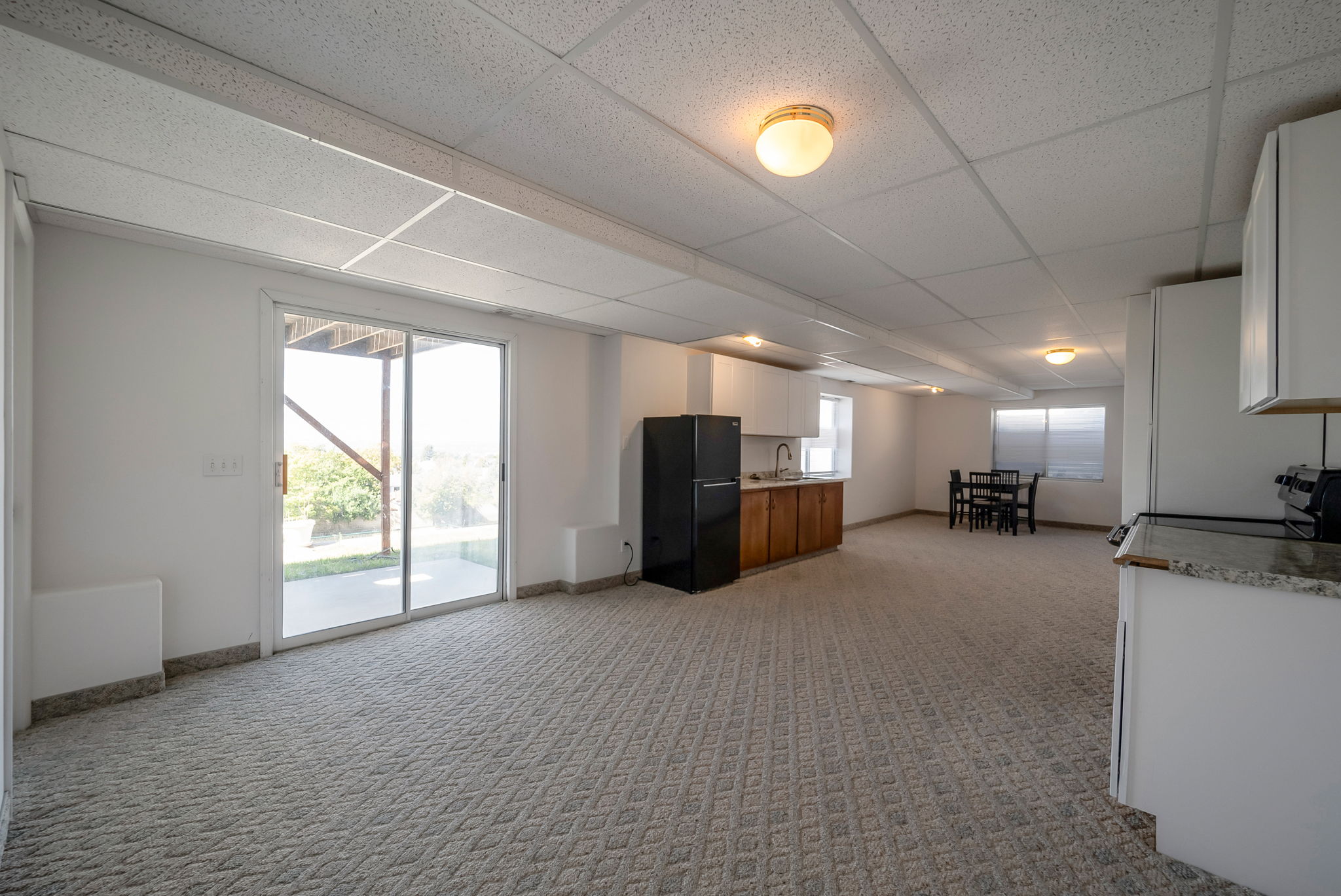 Living area with a drop ceiling and light carpet