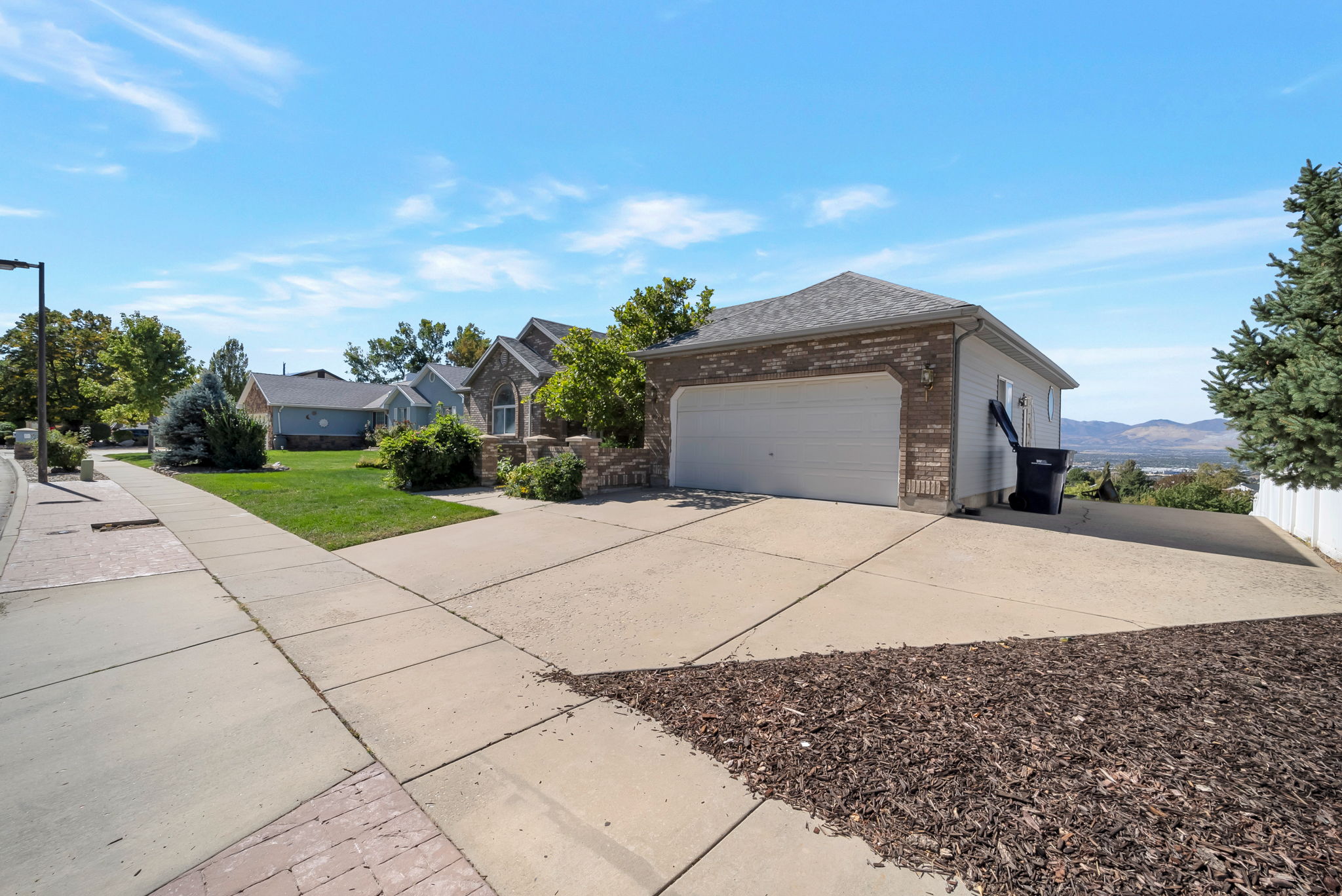 View of side of property featuring brick siding, concrete driveway, a lawn, and a garage