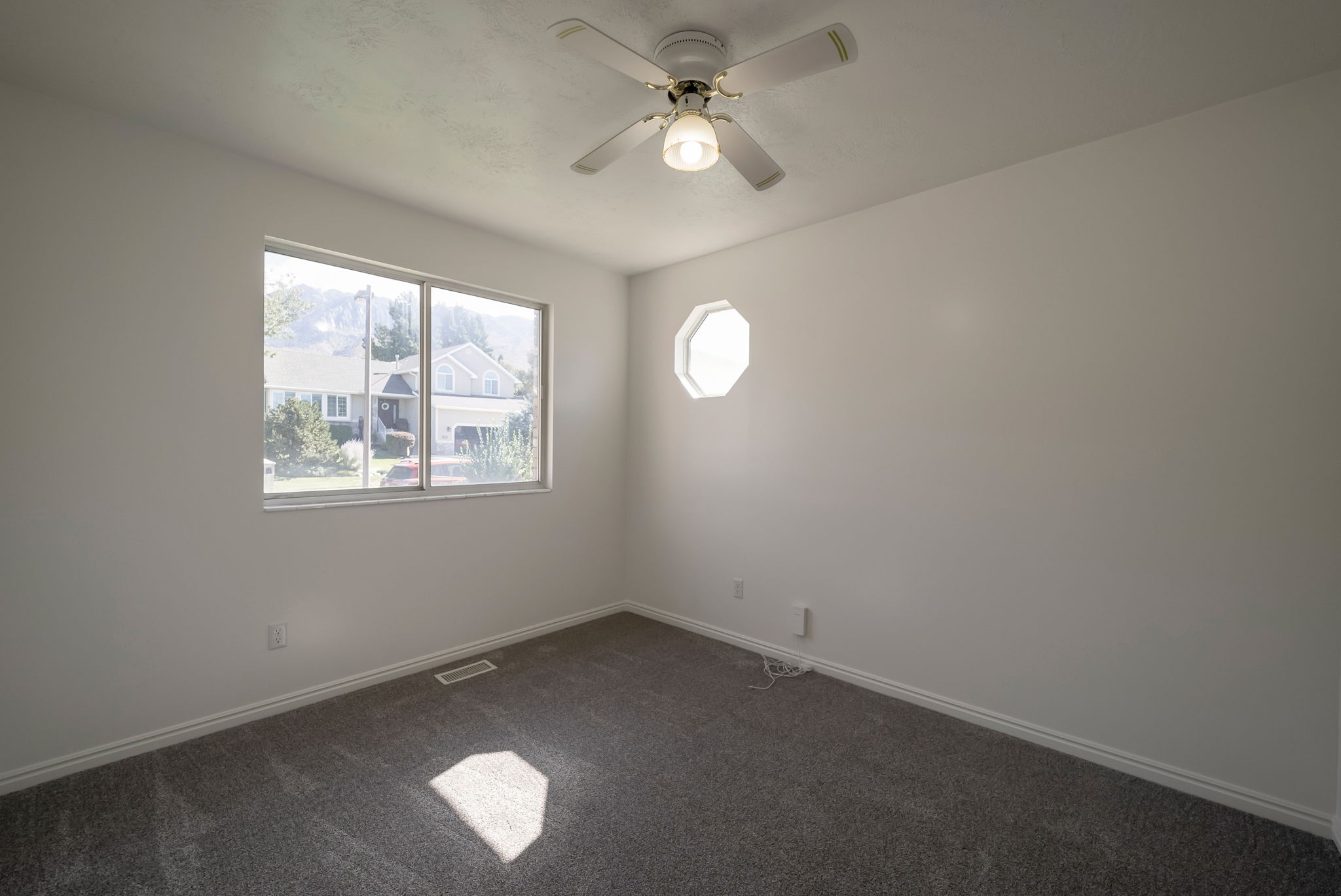 Empty room featuring dark carpet and a ceiling fan