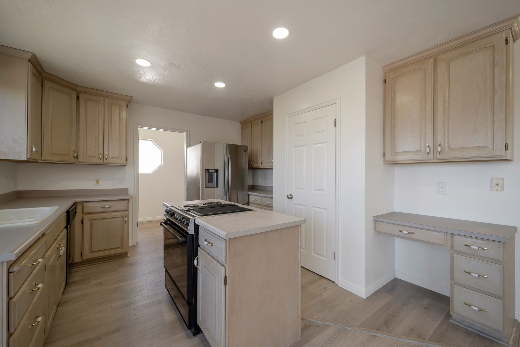 Kitchen with light wood finish cabinetry, stainless steel appliances, light countertops, light wood-style floors, and recessed lighting