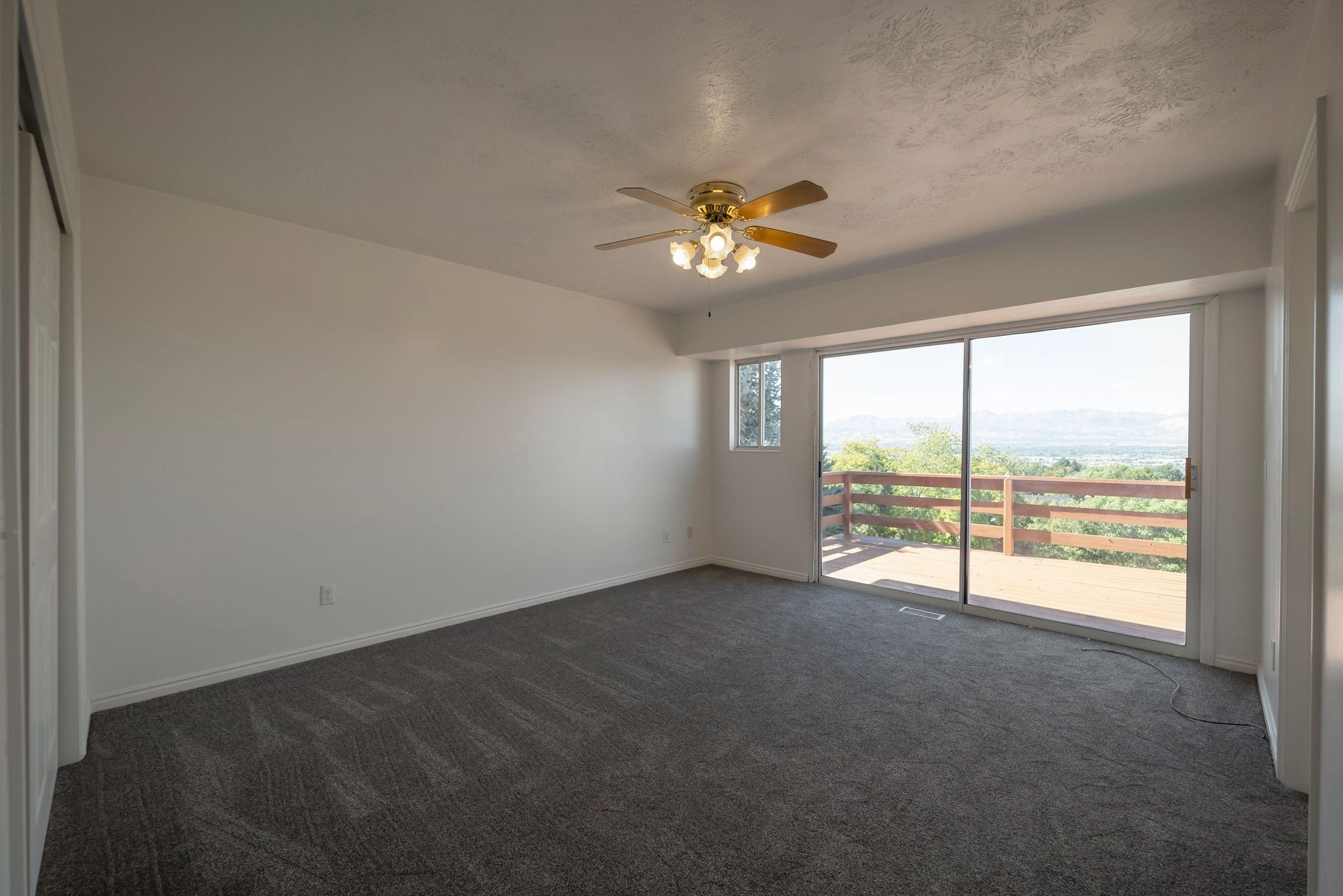 Spare room featuring dark colored carpet, ceiling fan, and a textured ceiling