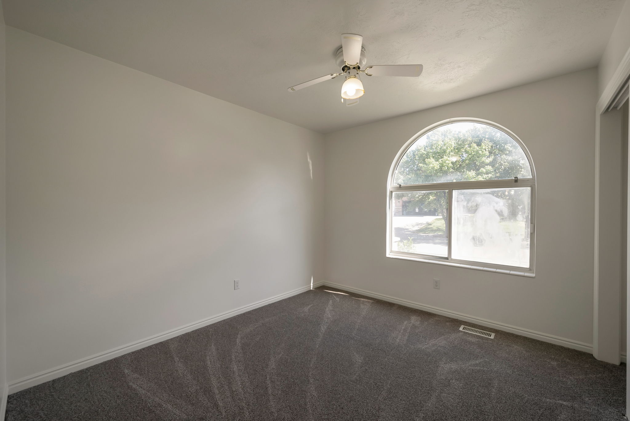 Empty room with dark carpet and ceiling fan