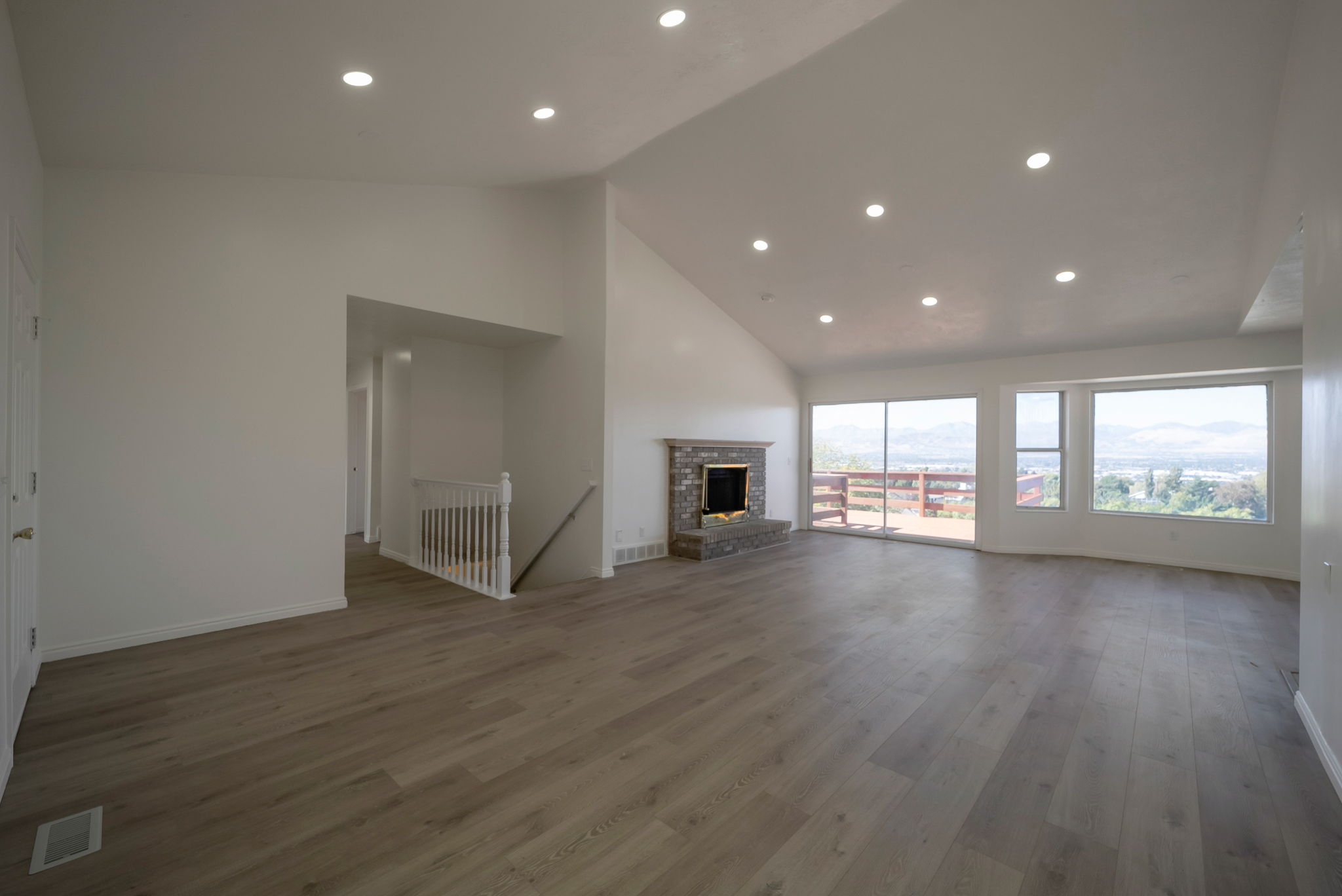 Unfurnished living room featuring a high ceiling, recessed lighting, dark wood-style flooring, and a fireplace