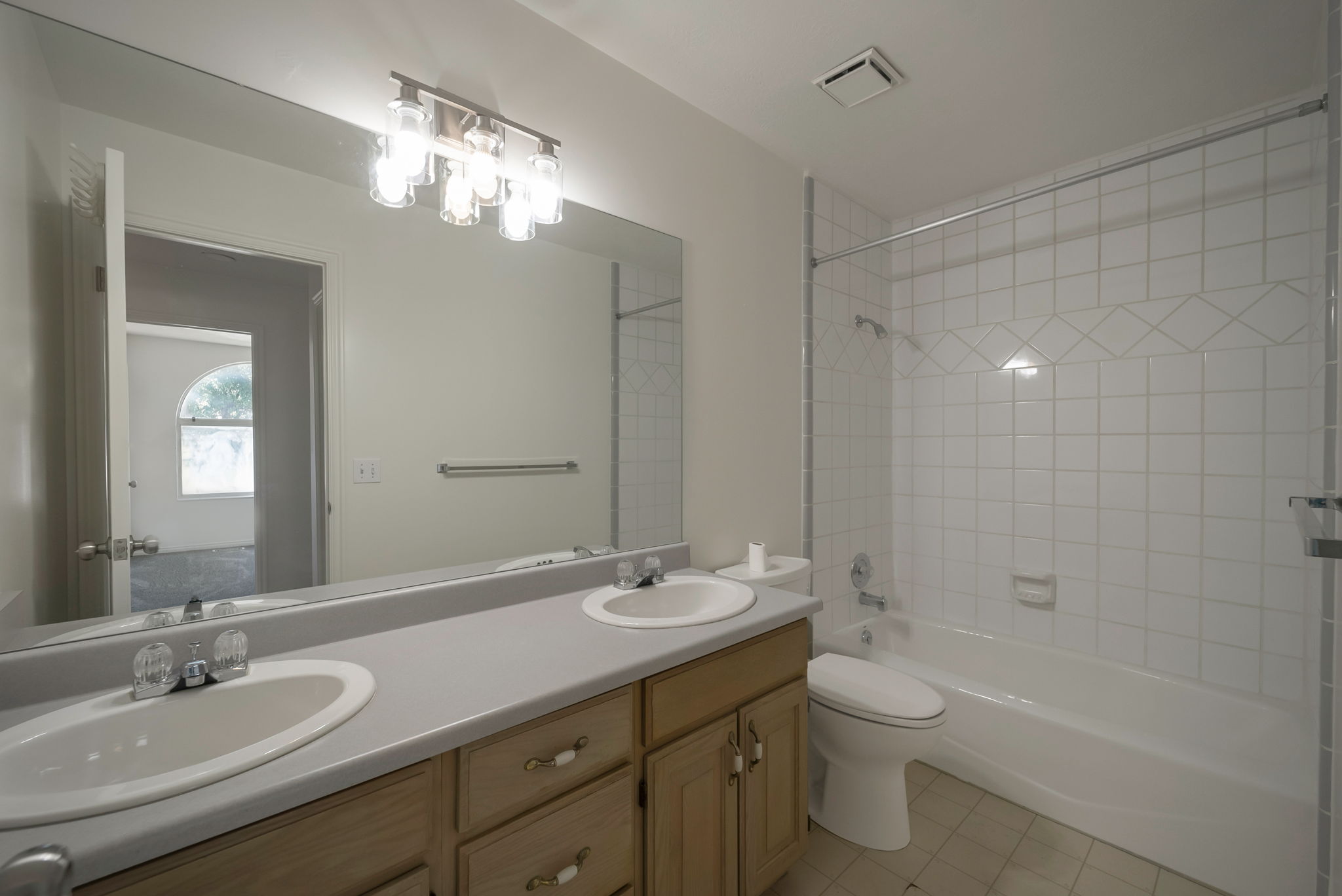 Bathroom with double vanity, shower / bathtub combination, and light tile patterned floors