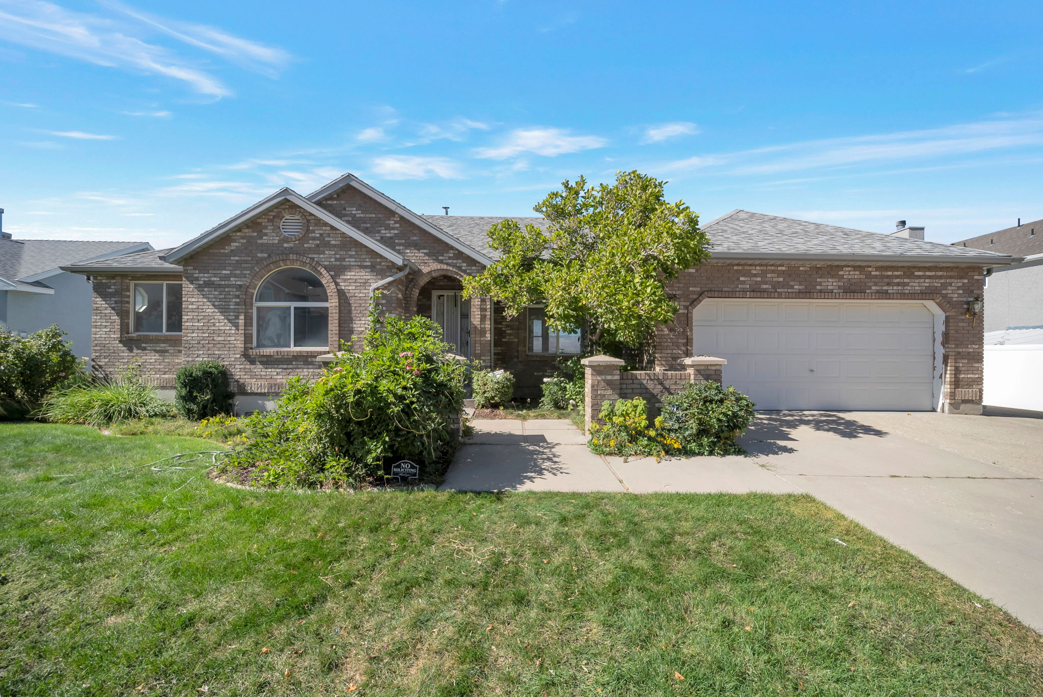 View of front facade featuring an attached garage, concrete driveway, brick siding, and a front lawn