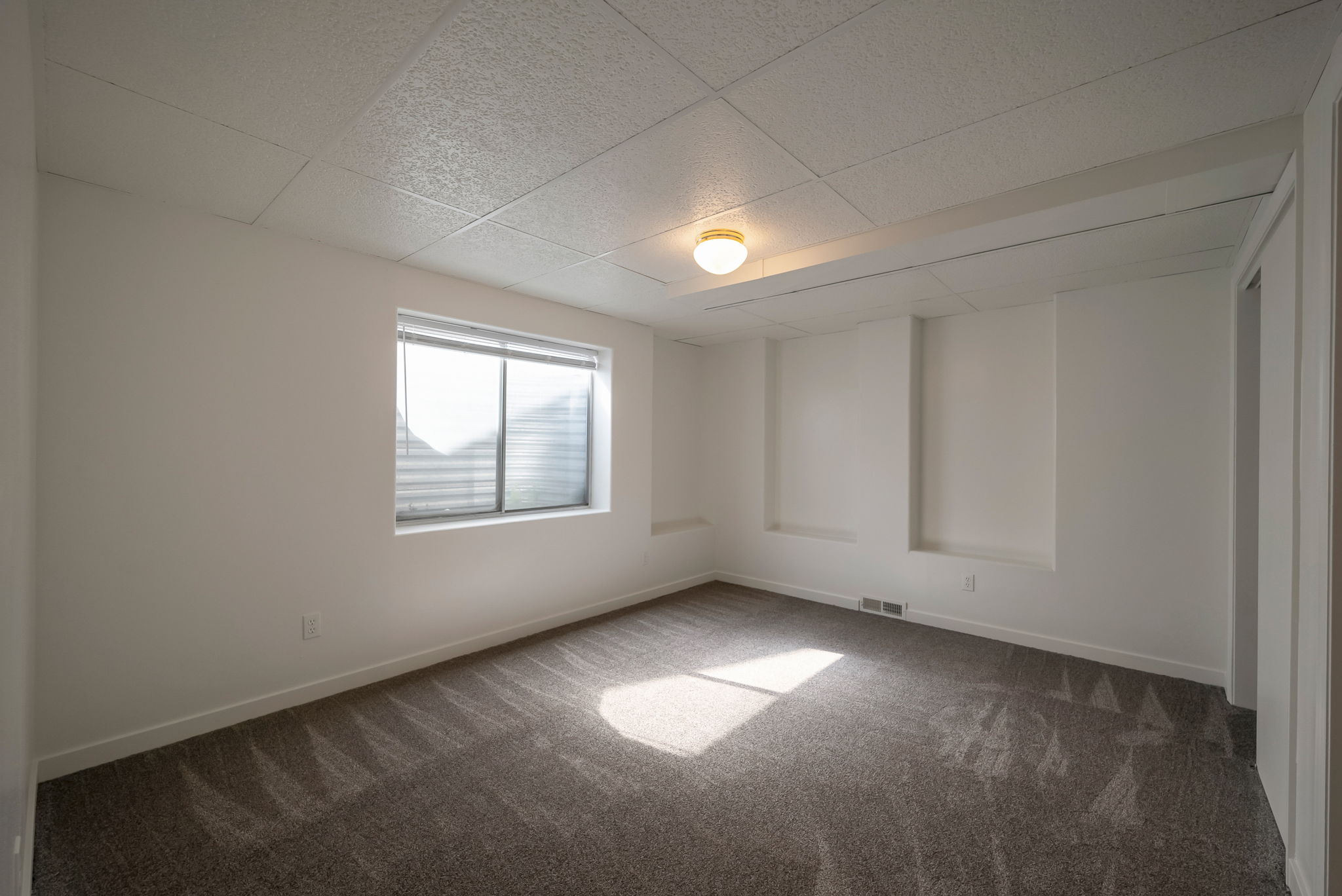 Carpeted empty room with a paneled ceiling and baseboards