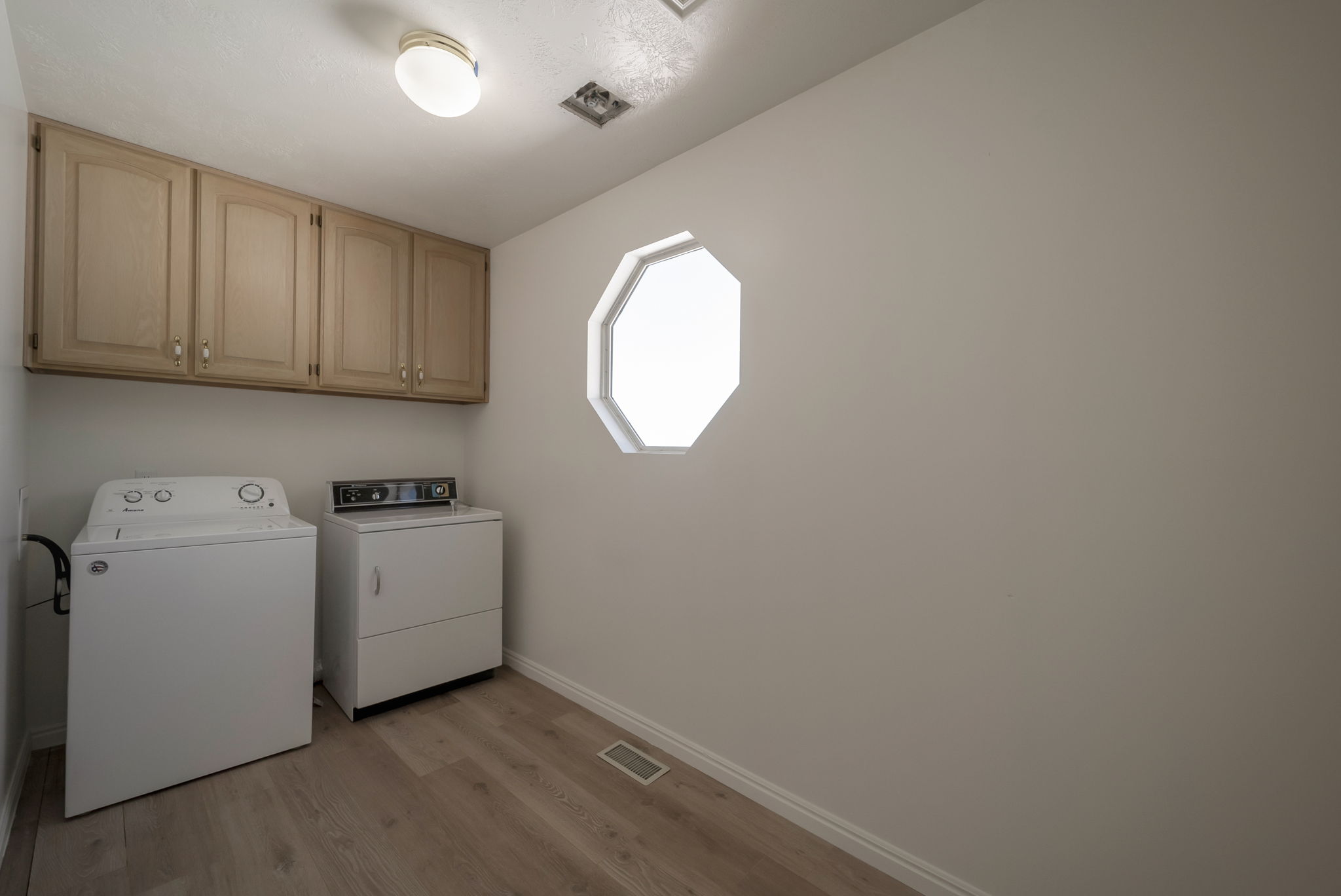 Laundry area with light wood finished floors, washer and dryer, and cabinet space