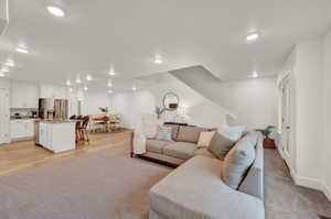 Living area with light carpet and recessed lighting