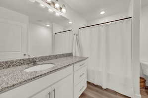 Full bath with curtained shower, vanity, light wood-style floors, and recessed lighting