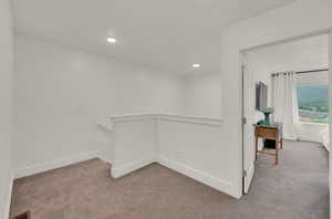 Hallway featuring light carpet, recessed lighting, and an upstairs landing