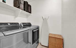 Laundry area with washer and clothes dryer and light wood-style floors