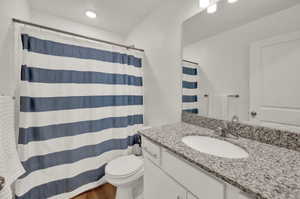 Full bath featuring vanity, a shower with shower curtain, and light wood-style floors