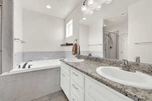 Bathroom featuring a marble finish shower, double vanity, a garden tub, and recessed lighting