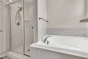 Bathroom with a marble finish shower and a garden tub