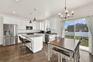 Kitchen featuring stainless steel appliances, white cabinets, light stone countertops, a kitchen island, and a kitchen breakfast bar