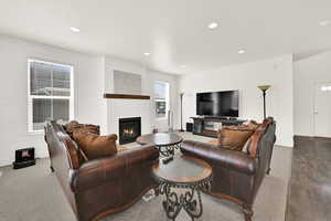 Carpeted living area featuring a large fireplace and recessed lighting