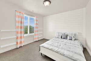 Carpeted bedroom featuring baseboards and wood walls