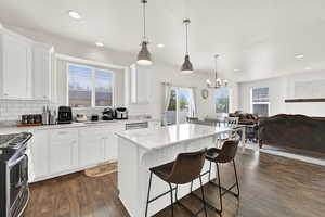 Kitchen featuring a kitchen island, open floor plan, light stone countertops, stainless steel appliances, and a kitchen bar