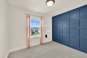 Unfurnished bedroom featuring a decorative wall and carpet flooring
