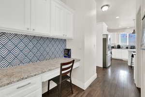 Home office featuring built in desk, dark wood-type flooring, and recessed lighting