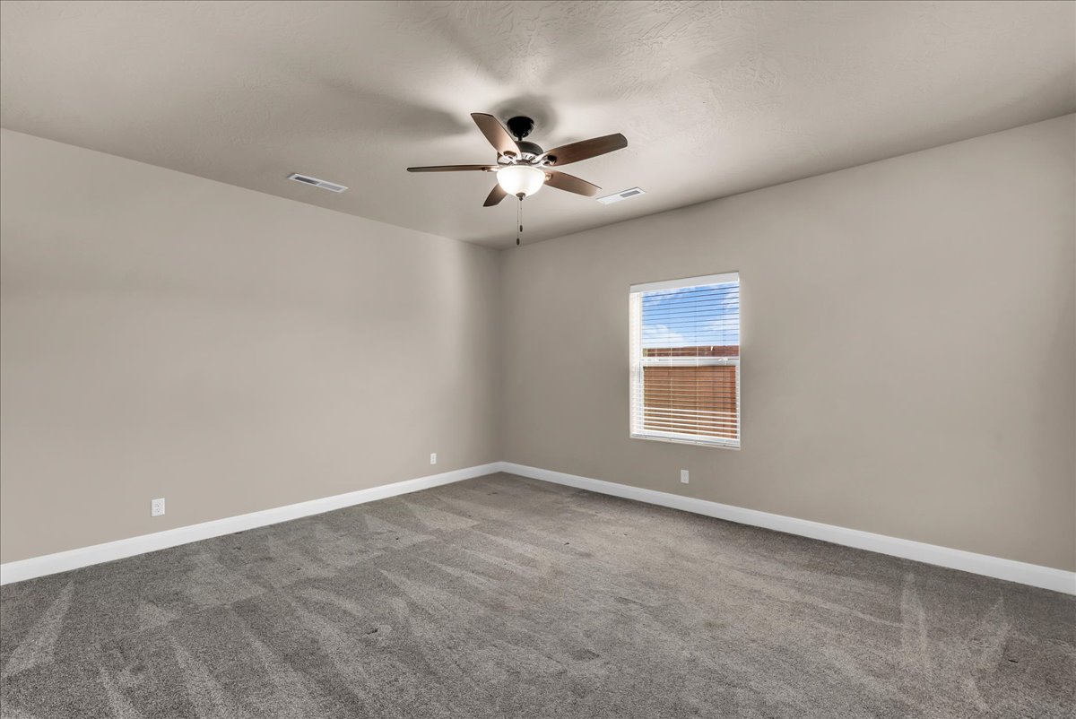Carpeted empty room with ceiling fan and baseboards