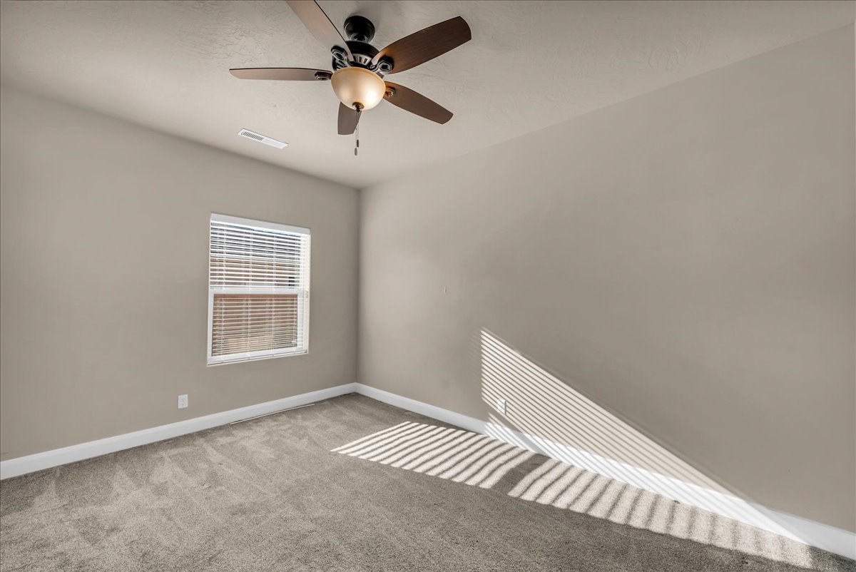 Unfurnished room featuring ceiling fan and light carpet