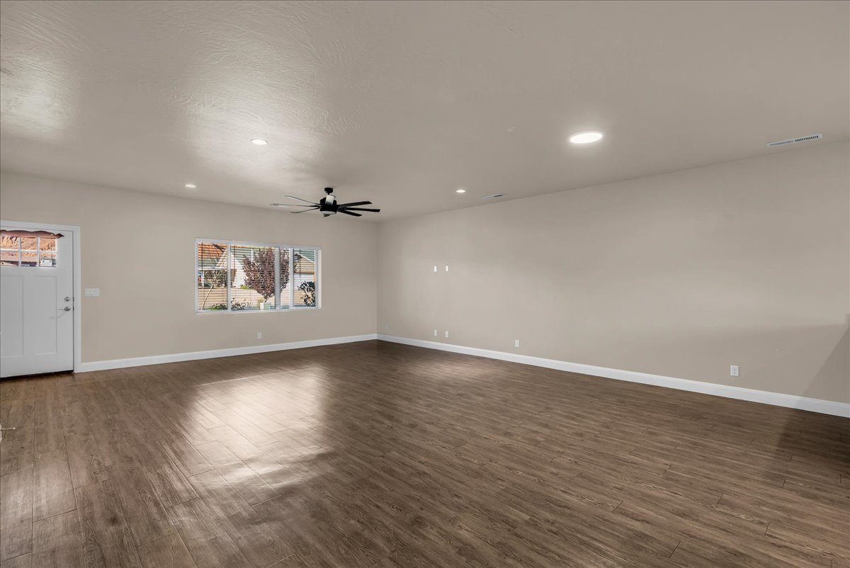 Unfurnished living room featuring dark wood-style floors, recessed lighting, and ceiling fan