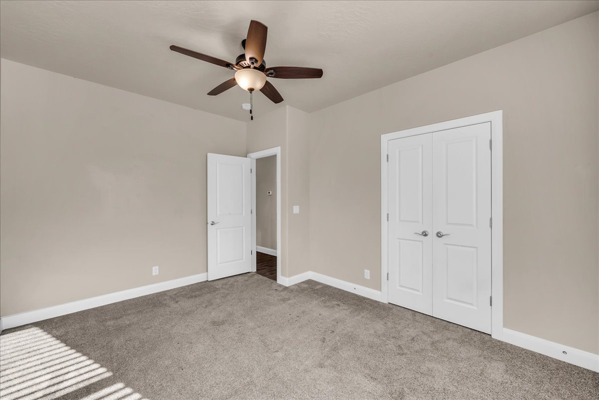 Unfurnished bedroom with light colored carpet, ceiling fan, and a closet