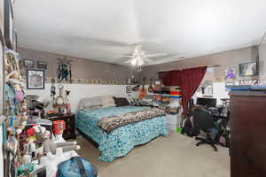 Bedroom featuring an office area, light colored carpet, and a ceiling fan