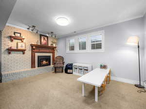 Living Area featuring brick wall, carpet flooring, ornamental molding, and a brick fireplace