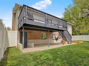 Back of property with a fenced backyard, a patio area, brick siding, and a wooden deck