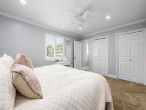 Carpeted bedroom with two closets, crown molding, recessed lighting, and ceiling fan