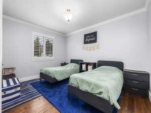 Bedroom featuring crown molding and dark wood finished floors