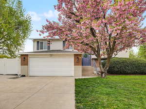 Front facing view with brick siding, concrete driveway, and an attached garage