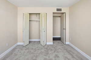 Unfurnished bedroom with light colored carpet and a closet