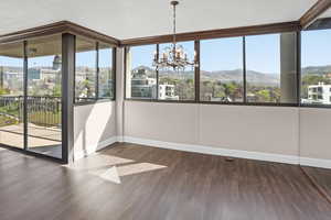 Unfurnished dining area featuring a chandelier, dark wood-style flooring, and healthy amount of natural light