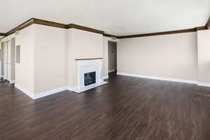 Unfurnished living room featuring a high end fireplace, ornamental molding, and dark wood-type flooring