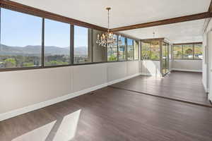 Unfurnished dining area featuring suspended lighting, dark wood-style flooring, and a mountain view