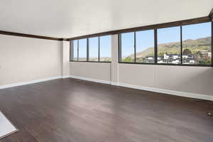 Spare room with a mountain view, dark wood-type flooring, and crown molding