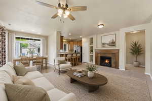 Living area featuring a fireplace with wood mantel surround, built-in shelving, and a ceiling fan