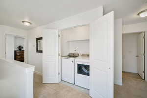 Laundry area with light carpet and independent washer and dryer