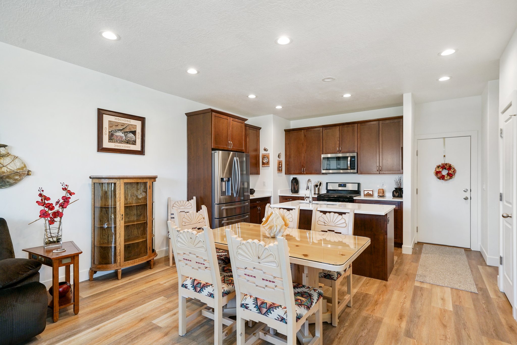Kitchen with a kitchen island with sink, stainless steel appliances, light wood-style flooring, dark wood finish cabinetry, and recessed lighting