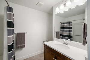 Full bath with vanity, a shower with shower curtain, light tile patterned floors, water heater, and a textured ceiling