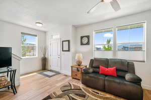 Living area featuring light wood finished floors, a ceiling fan, and a textured ceiling