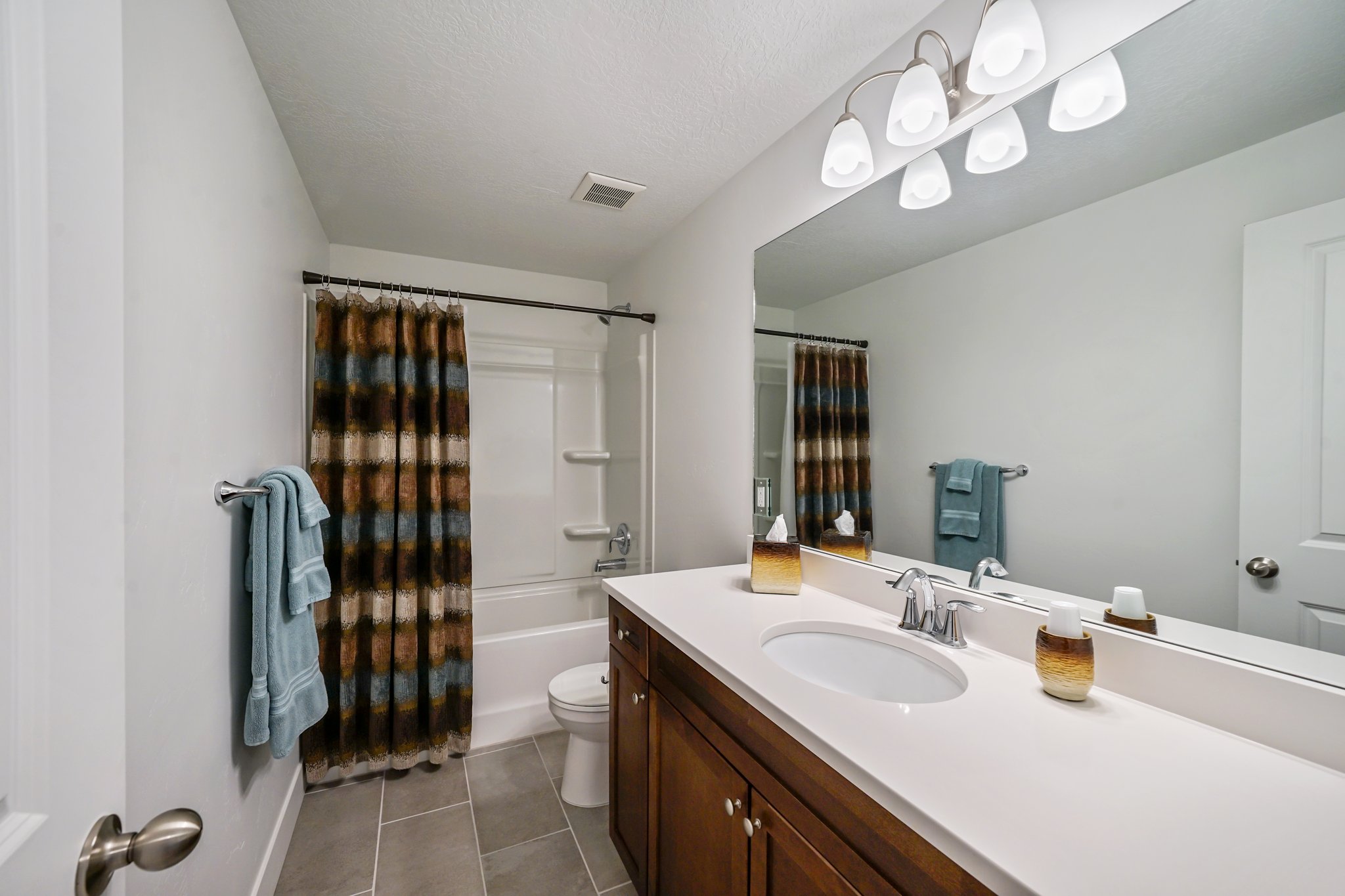 Bathroom with vanity, shower / bath combination with curtain, and dark tile patterned floors