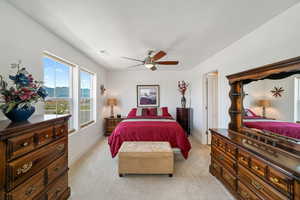 Bedroom with light colored carpet, a mountain view, ceiling fan, and a textured ceiling