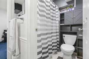 Bathroom featuring curtained shower and light marble finish flooring